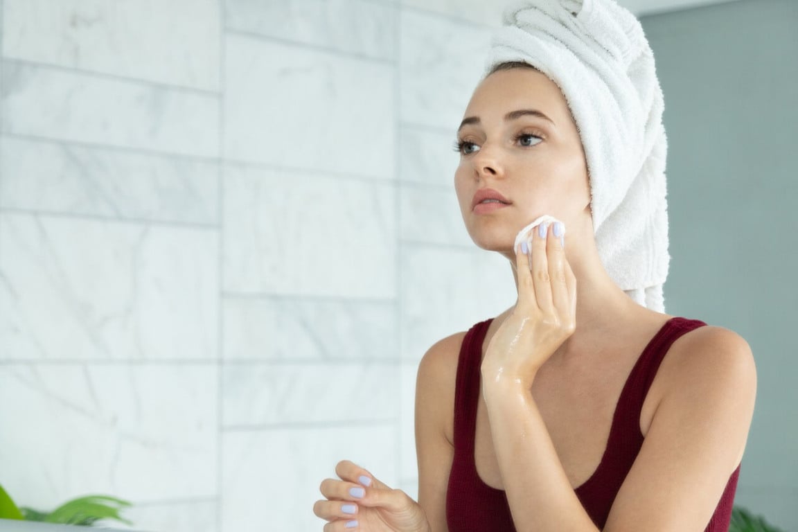 Mulher limpando rosto com algodão