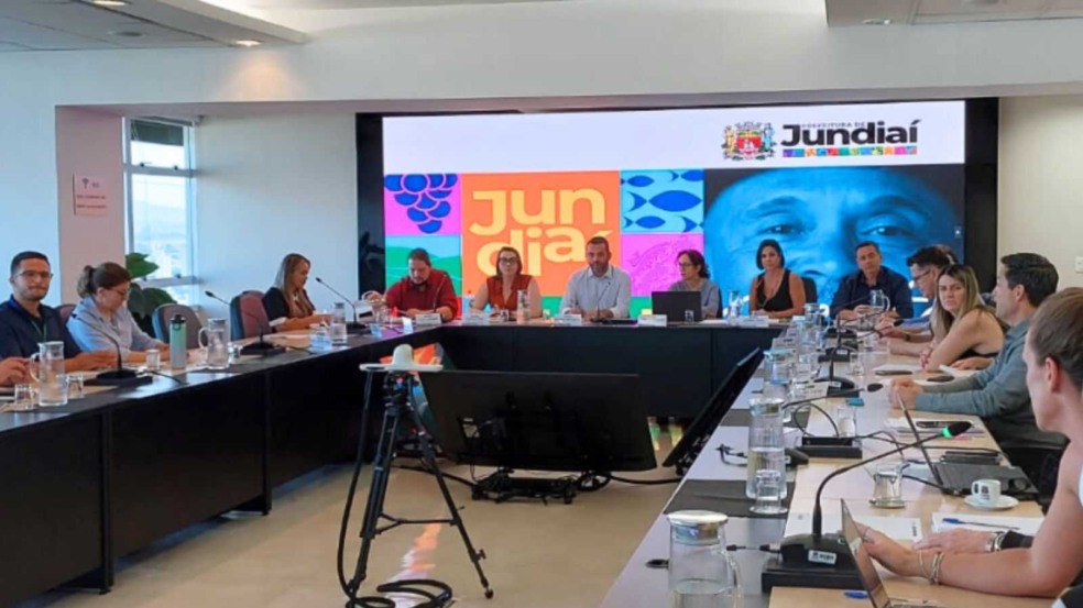 Reunião da ACE com o prefeito de Jundiaí e secretários municipais, em uma sala com telão exibindo a marca da cidade.