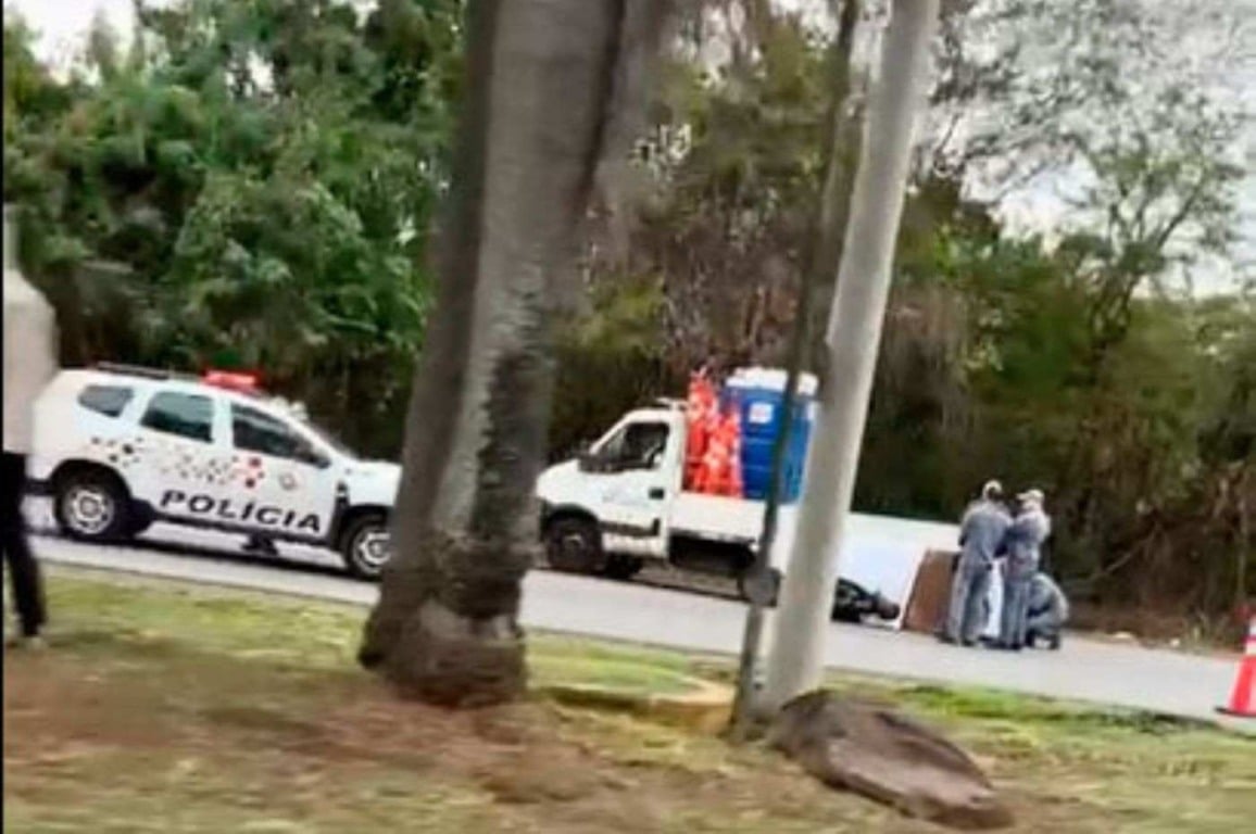 Viatura da polícia e caminhão de sinalização em acidente fatal na Marginal do Rio Jundiaí com motociclista em Várzea Paulista.