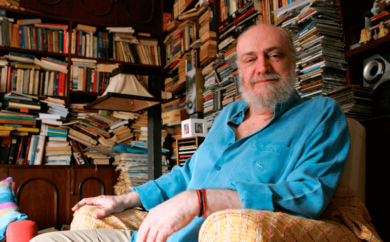 Aldir Blanc sentado em poltrona de biblioteca Aldir Blanc sentado em poltrona de biblioteca