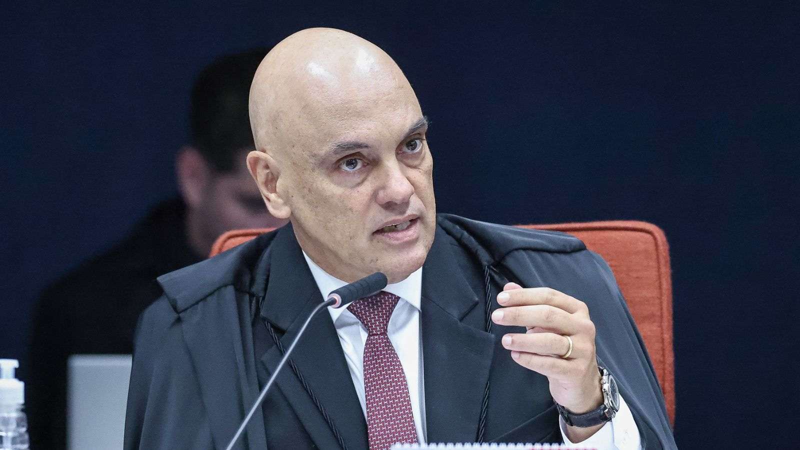 Ministro Alexandre de Moraes, do STF, fala ao microfone durante sessão, usando toga preta e gravata vermelha.