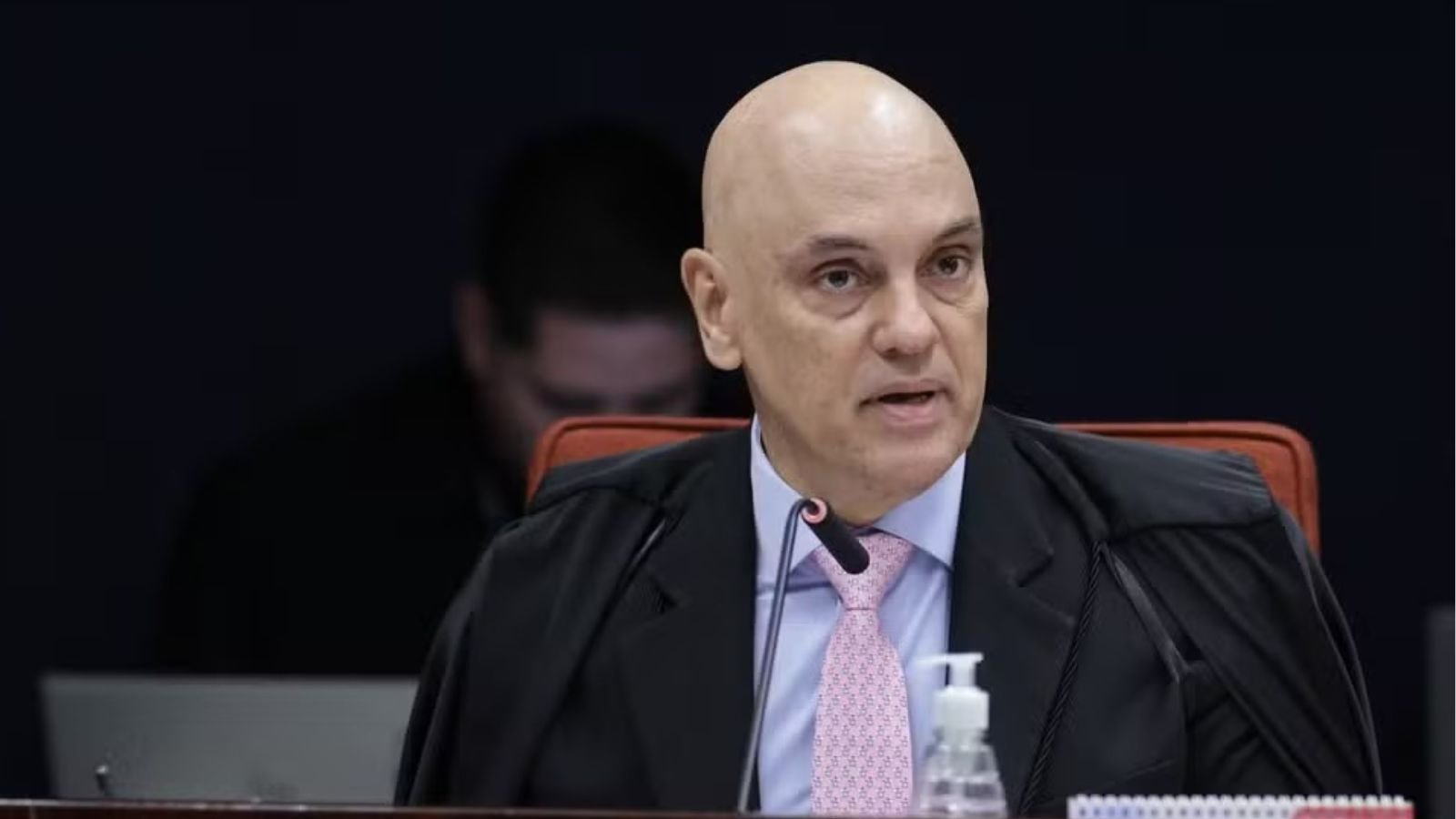 Ministro Alexandre de Moraes, do STF, fala durante sessão no tribunal, usando toga preta e gravata rosa clara.