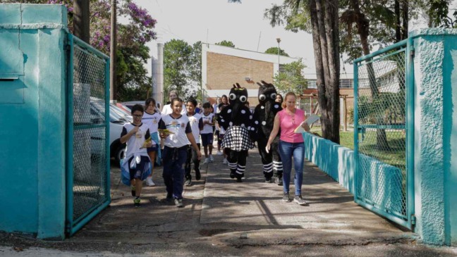 Crianças e personagens da dengue indo realizar ações.