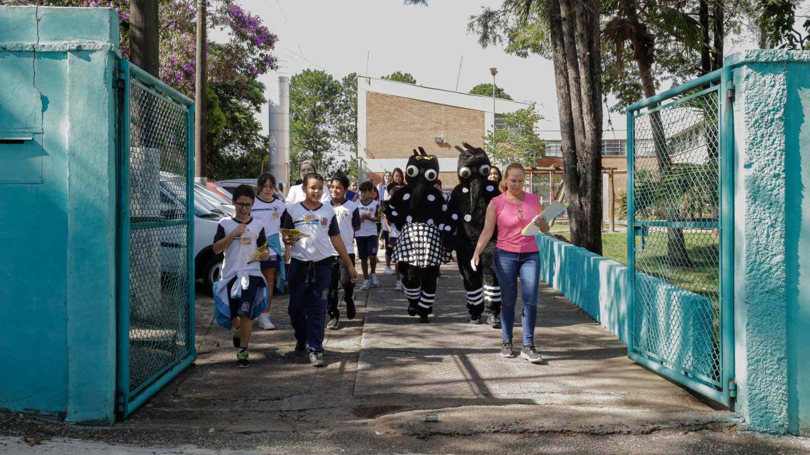 Crianças e personagens da dengue indo realizar ações.