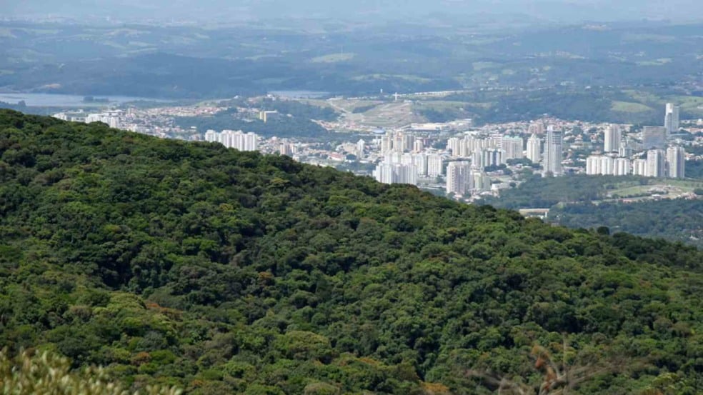 Vista aérea de Jundiaí com a Serra do Japi em primeiro plano e prédios da cidade ao fundo.