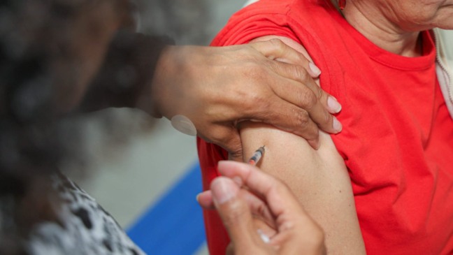 Aplicação de vacina no braço de uma pessoa, em ação de combate à gripe.
