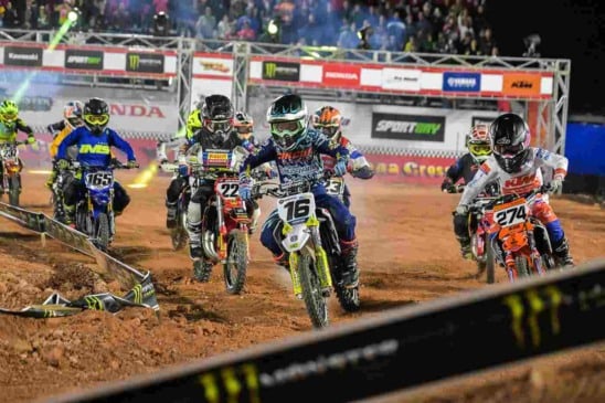 Competição de motocross na Jundiaí Arena Cross, com diversos pilotos em motocicletas de diferentes equipes, disputando em pista de terra.