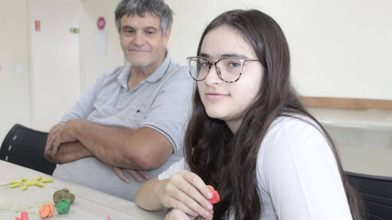 Pai e filha participam de atividade de modelagem com massinha, promovendo criatividade e interação familiar na APAE Jundiaí.