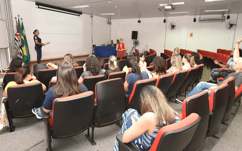 Auditório ocupada por mulheres; guarda fala no palco