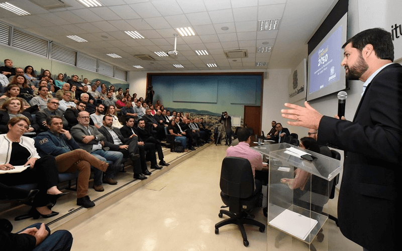 Prefeito de Jundiaí à direita falando a participantes de encontro anterior do Fórum Jundiaí.