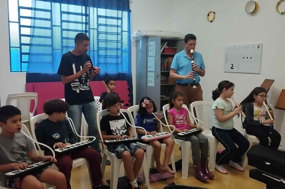 Crianças tocando instrumentos musicais em aula de música