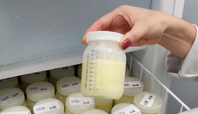 Mão segurando frasco de leite