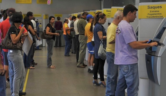 Pessoas em caixa eletrônico da Caixa Econômica Federal