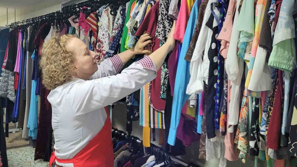 Mulher arrumando arara de roupas.