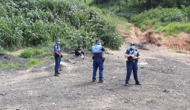 Foto de homem em área de mato com guardas municipais
