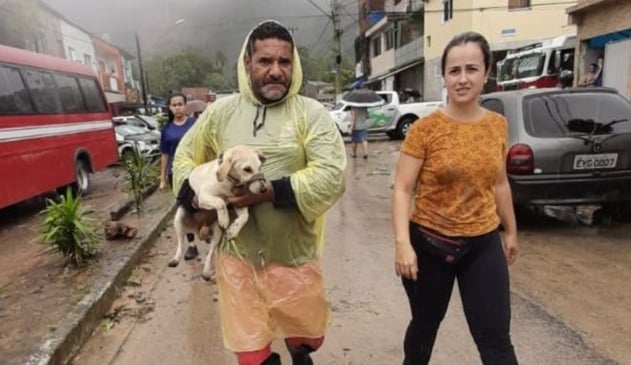 Foto de homem carregando cachorro no colo ao lado de mulher