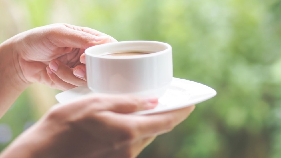 Mão feminina segurando café.