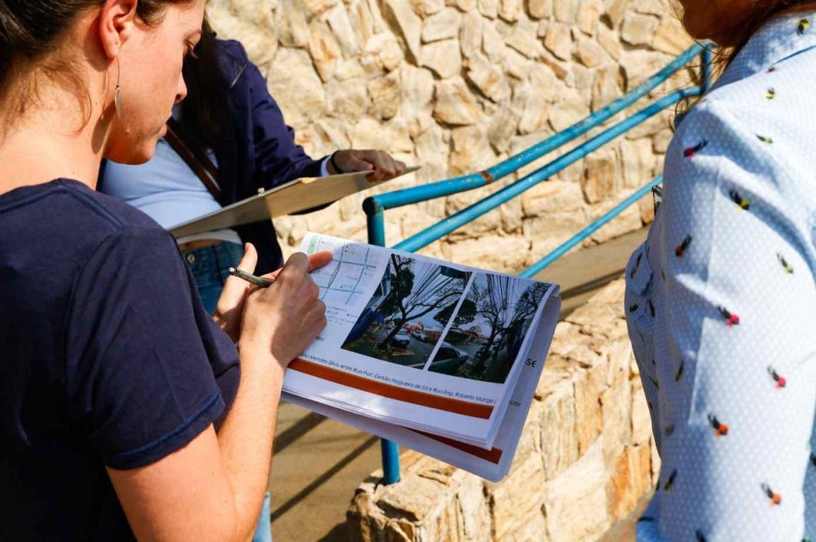 Técnicos da prefeitura de Jundiaí verificam obras de acessibilidade nas calçadas do Anhangabaú com plantas em mãos.