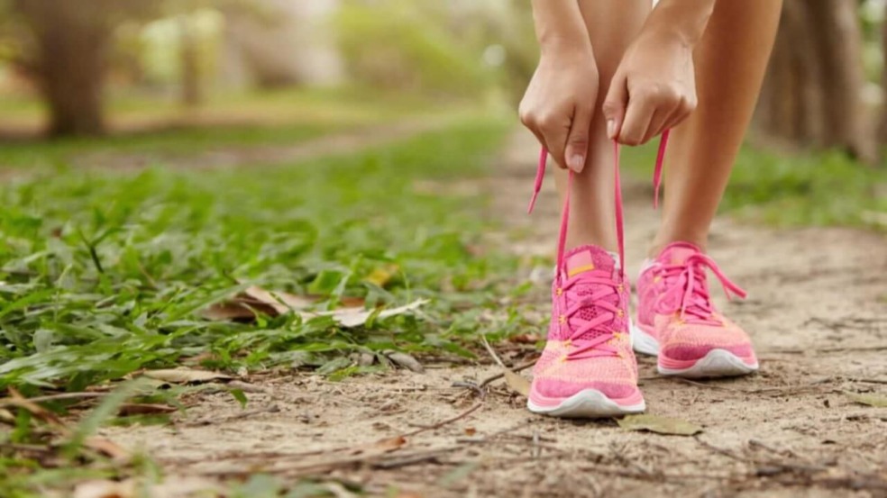 Foto de uma mulheres amarrando o tênis cor de rosa Foto de uma mulheres amarrando o tênis cor de rosa