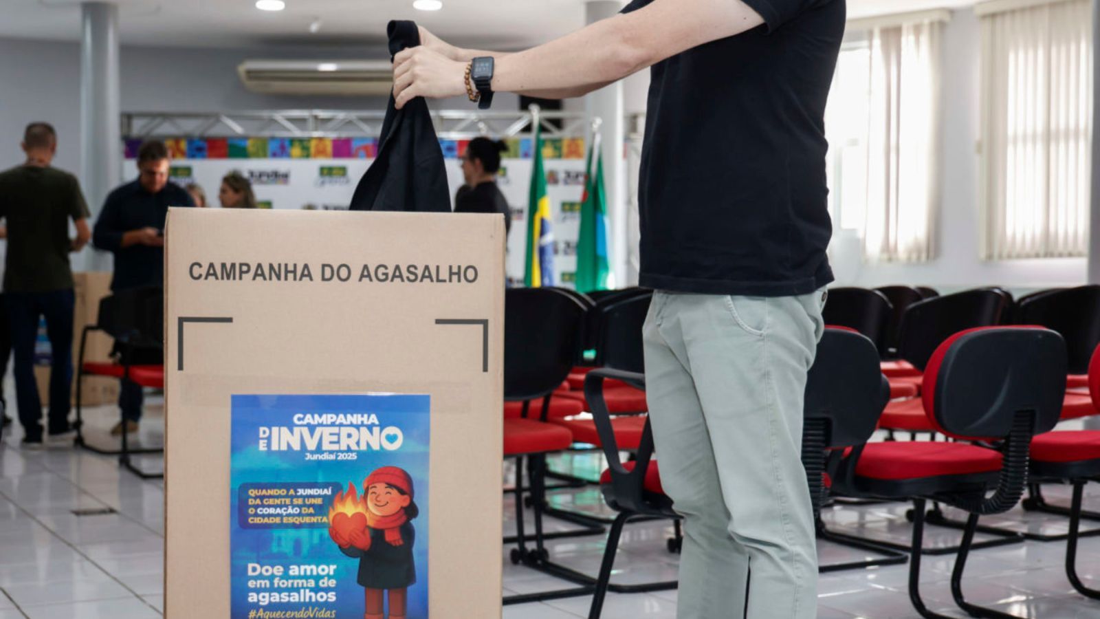 Homem dando agasalho em campanha de Jundiaí.