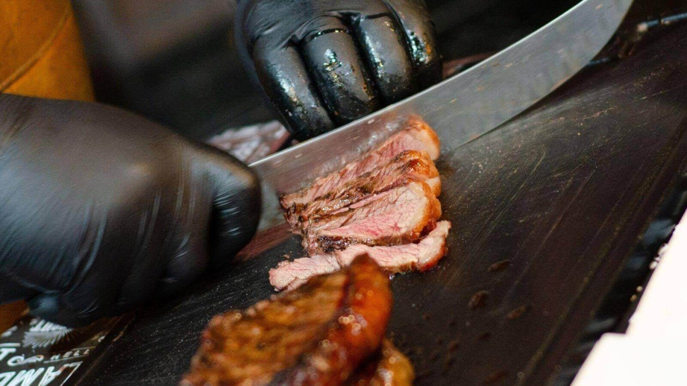 Churrasqueiro cortando carne