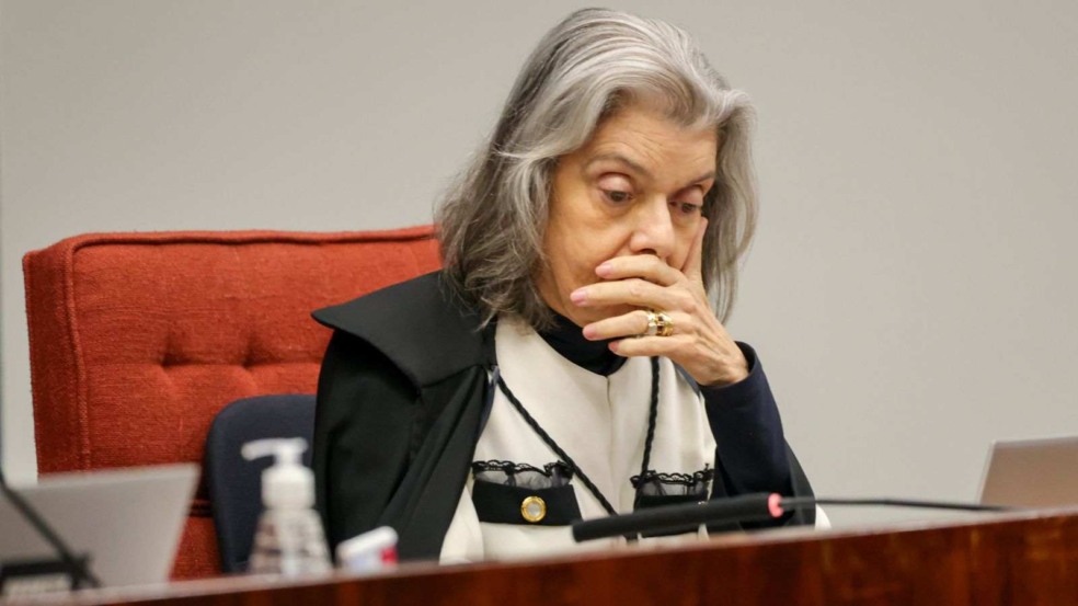 Ministra Cármen Lúcia, do STF, em gesto pensativo durante sessão, com a mão sobre a boca e toga preta.