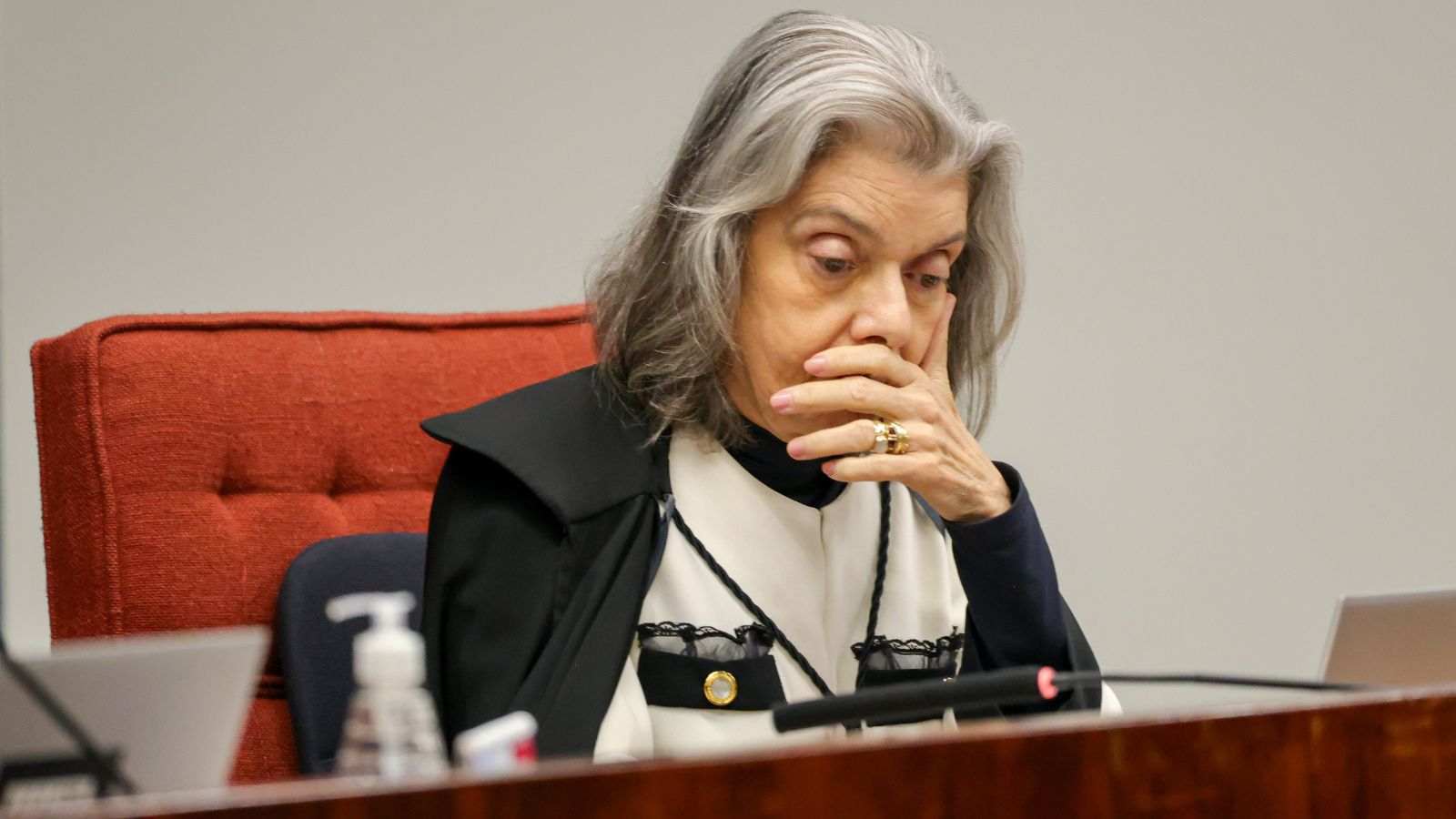 Ministra Cármen Lúcia, do STF, em gesto pensativo durante sessão, com a mão sobre a boca e toga preta.