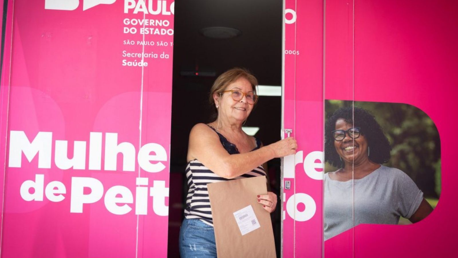 Mulher com exame em mãos saindo da carreta da mamografia.