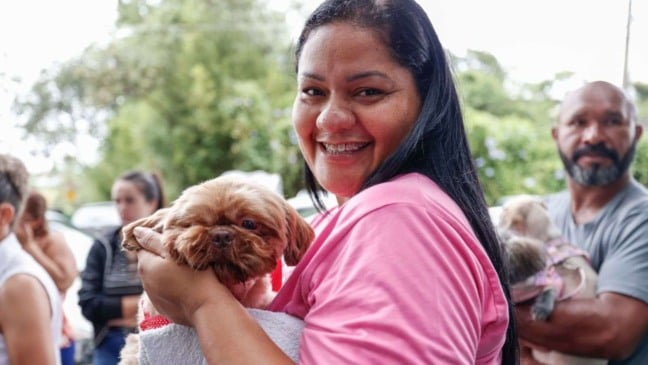 Mulher segurando o cachorro.