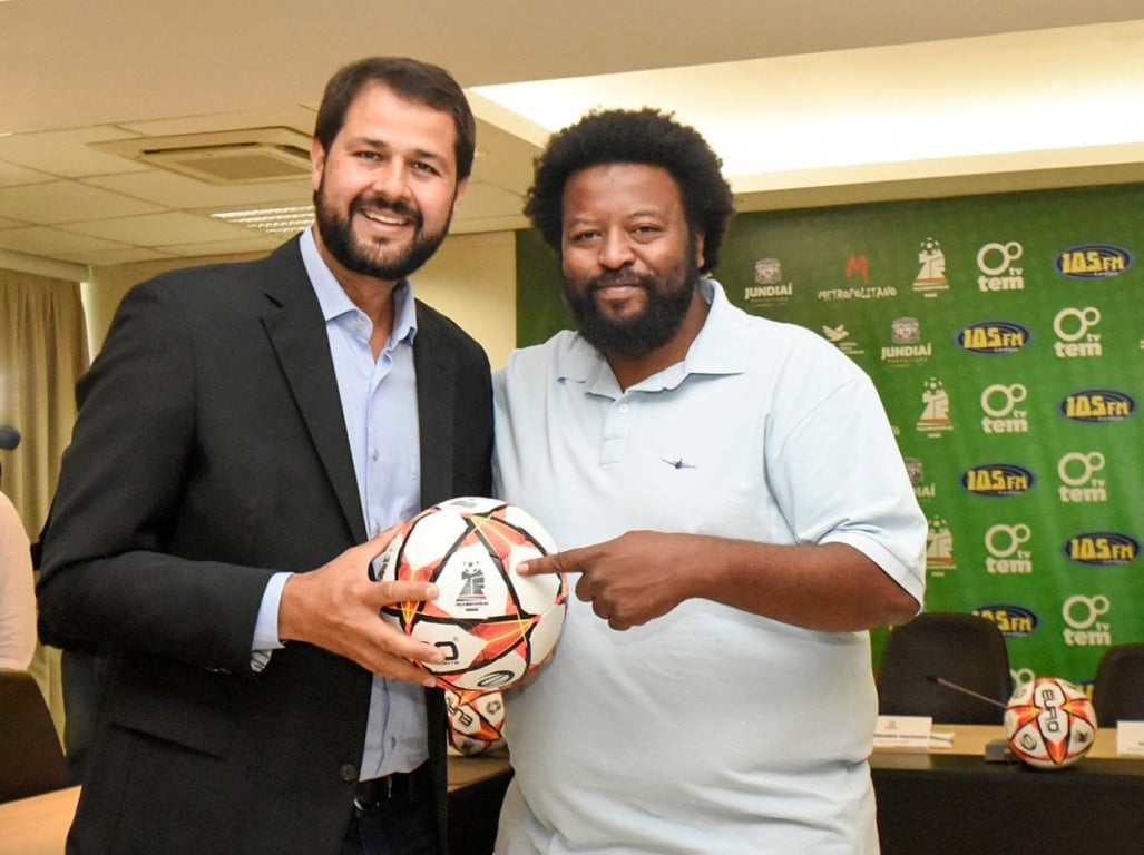 um homem branco e um homem negro segurando uma bola de futebol