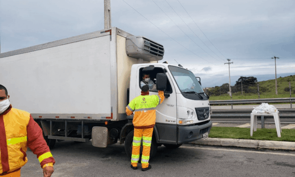 Funcionário da CCR atende caminhoneiro na beira de estrada