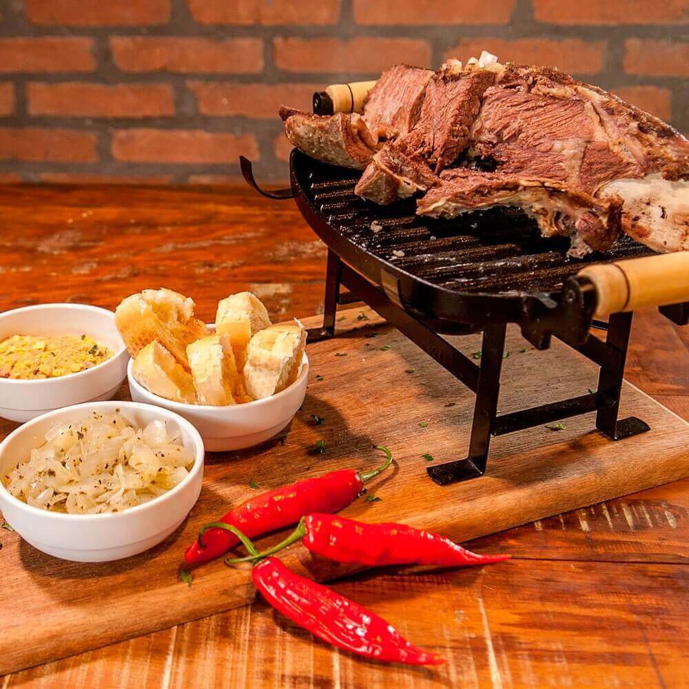 Mesa com petiscos e carne em mini churrasqueira