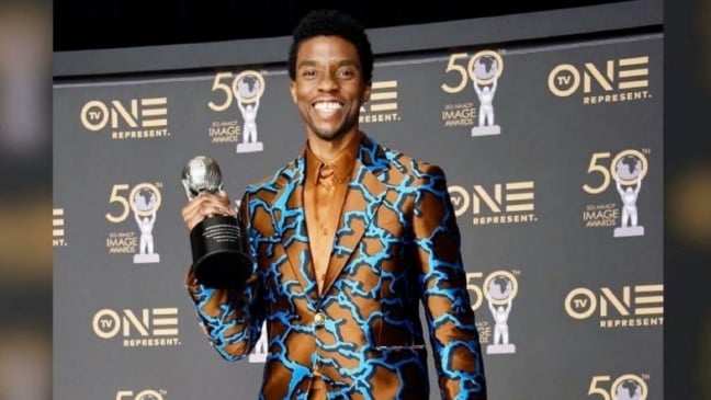 Ator Chadwick Boseman segurando um dos prêmios de atuação.