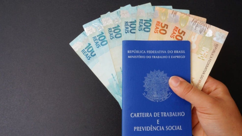 Carteira de trabalho com cédulas de cinquenta e cem reais.