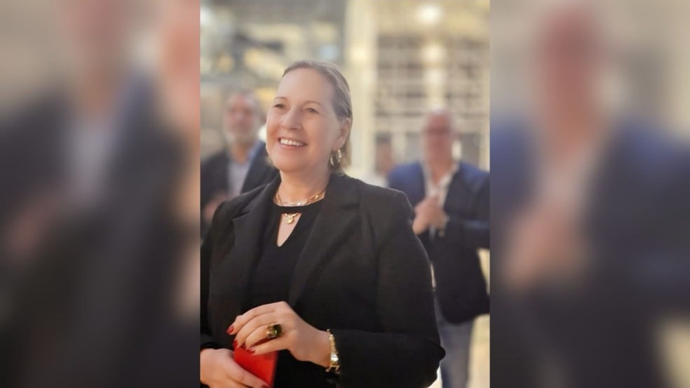 Mulher segurando caixa vermelha em evento.