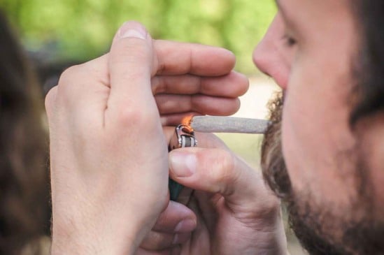 Homem acendendo um cigarro enrolado à mão com um isqueiro, relacionado à discussão sobre descriminalização do porte de drogas