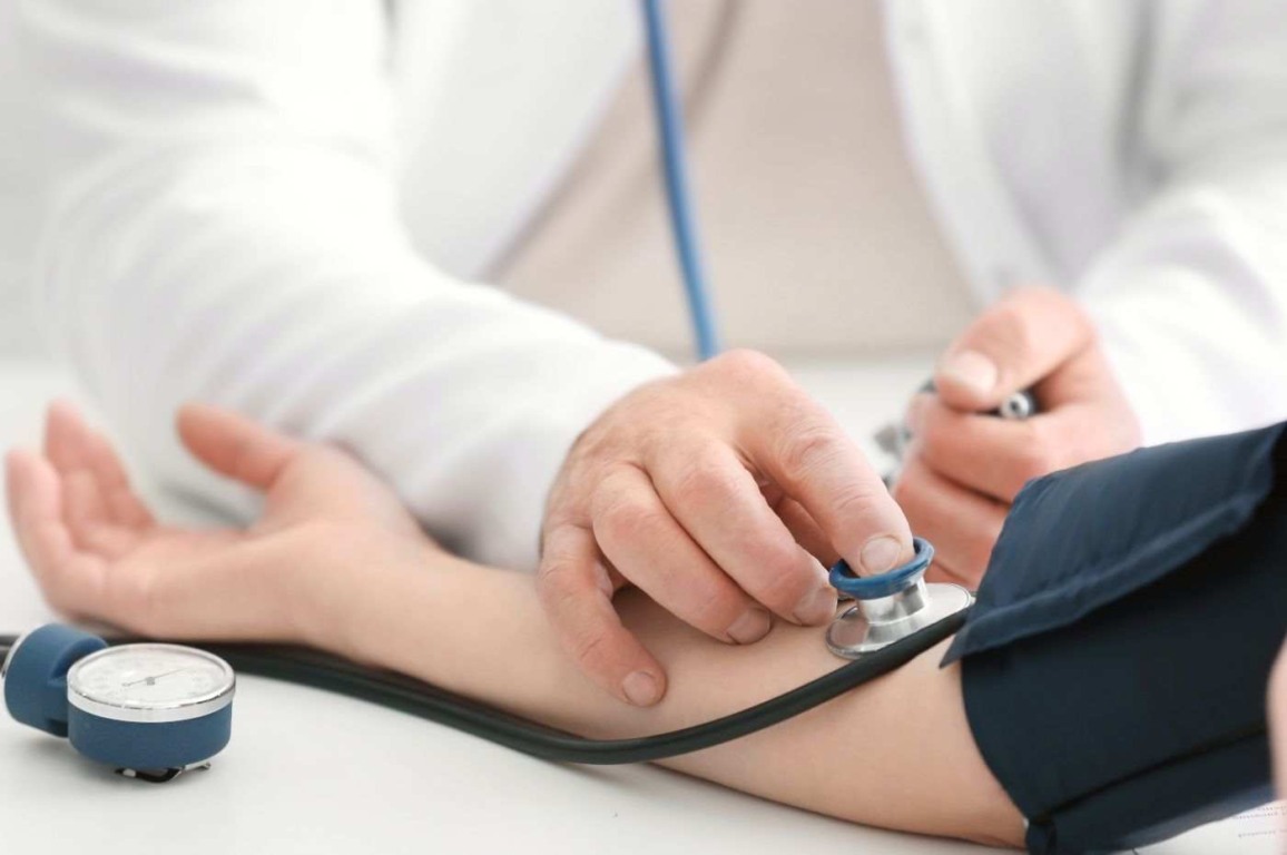 Médico medindo a pressão arterial de um paciente durante consulta, relacionado ao concurso para médicos especialistas em Jundiaí.