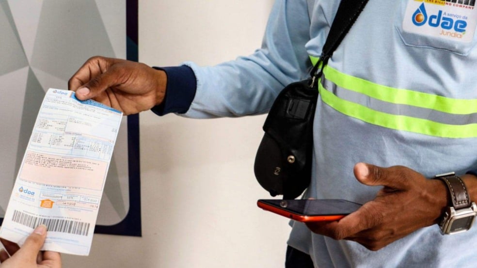 Servidor público entregando conta de água para outra pessoa.