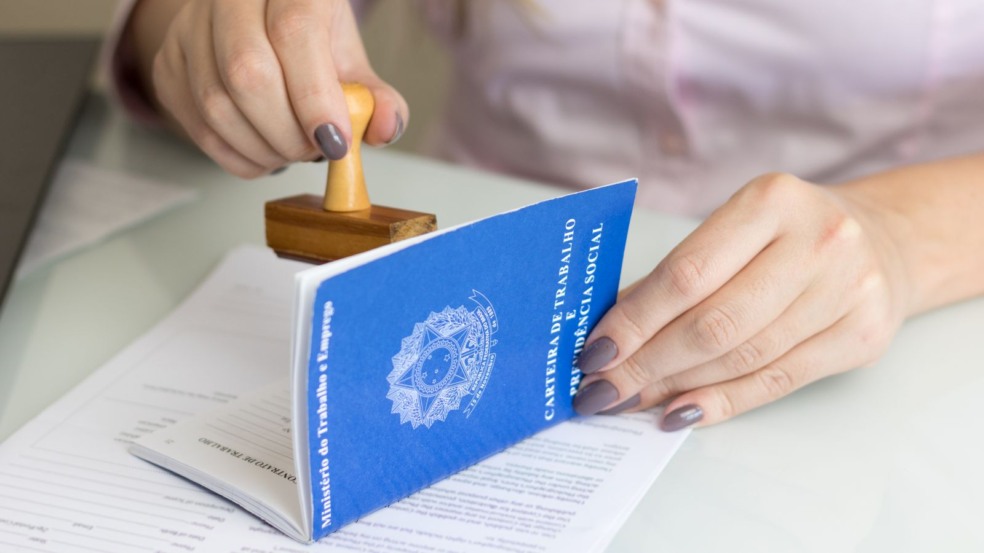 Mulher assinando carteira de trabalho.