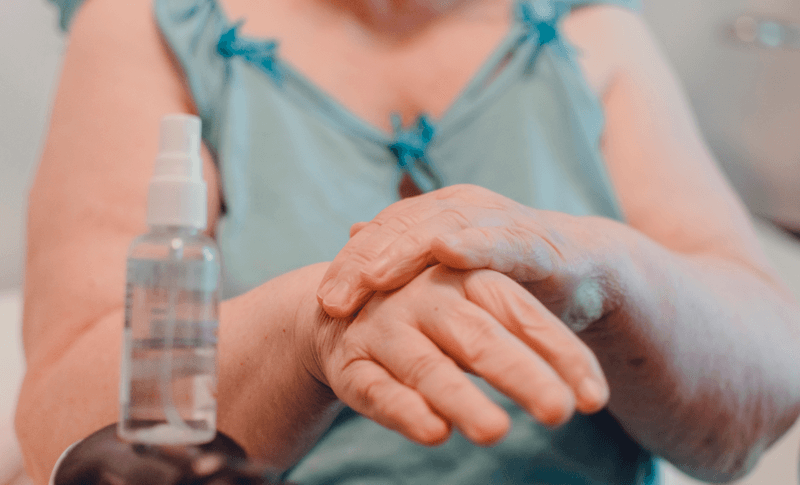 Idosa passando álcool em gel nas mãos