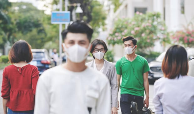 Pessoas andando na rua com máscaras