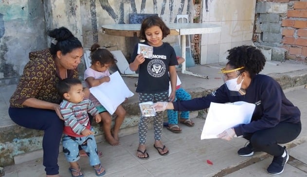 Foto de crianças recebendo máscaras de proteção