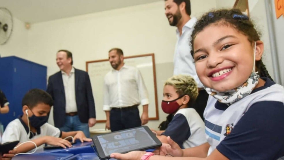 criança com sorriso no rosto e um tablet na mão
