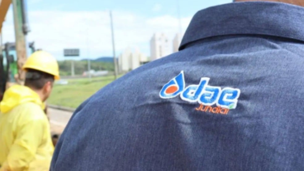 Funcionários da DAE Jundiaí em trabalho de manutenção de rede de água, com destaque para uniforme com logotipo da empresa.