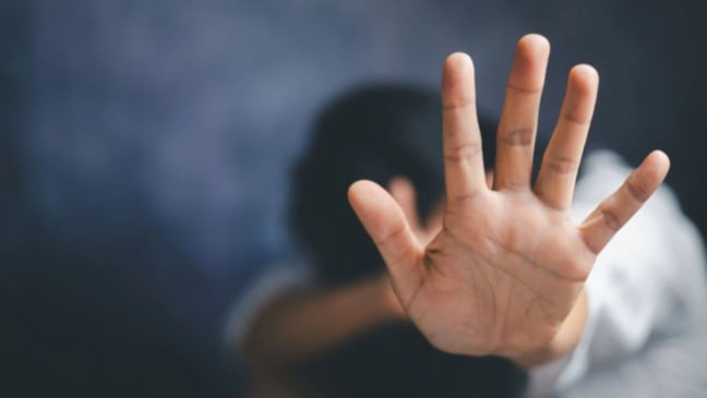 Mulher sentada em chão com a mão esticada.