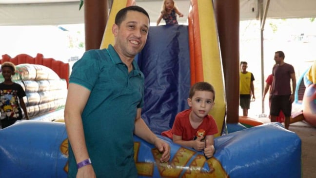 Criança, junto de seu pai, em brinquedo inflável.