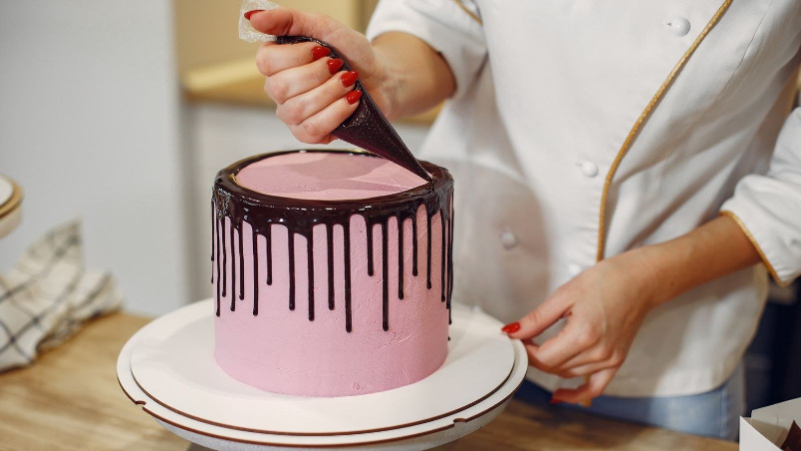 Mão de mulher confeitando bolo.