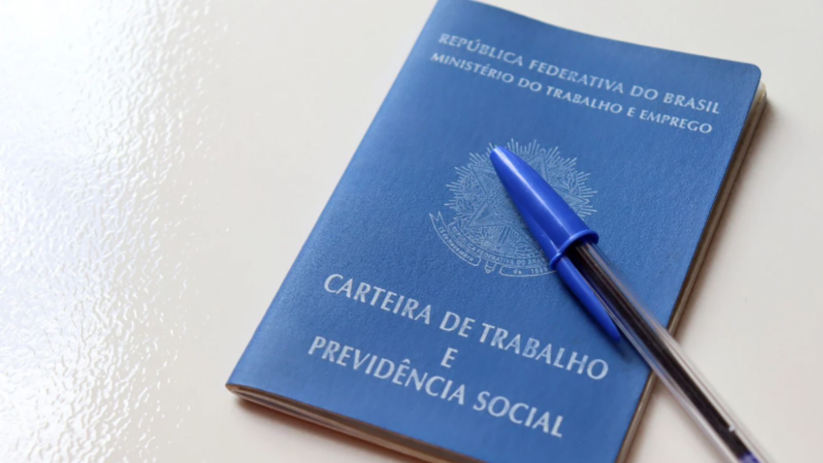 carteira de trabalho com caneta azul.