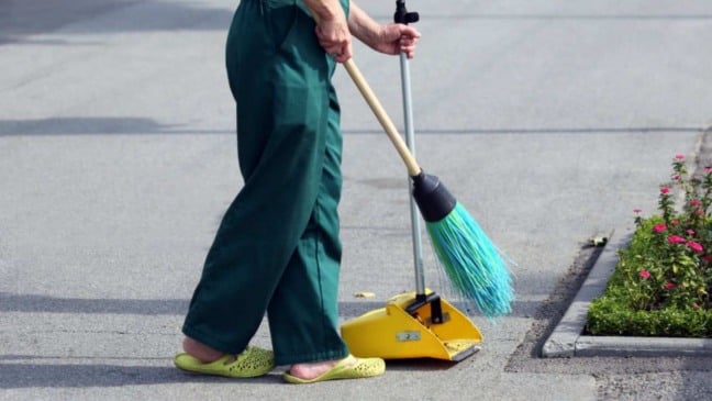 Ajudante geral varrendo a rua.