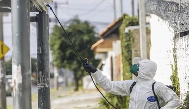 Foto de operário realizando desinfecção em ponto de ônibus